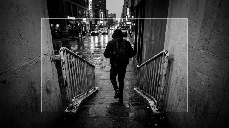 A person in motion, walking up a weathered concrete staircase in a bustling, rain-slicked city street at dusk, reflecting neon green lights, symbolizing business agility and strategic adaptation in dynamic markets.