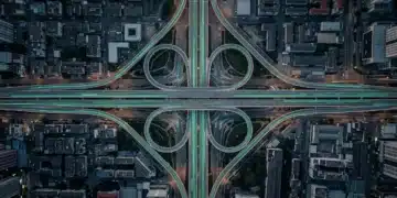 Aerial view of a city's highway network at dawn, showing dynamic green light trails from vehicles symbolizing future-forward business insights and proactive data analysis for growth strategies.