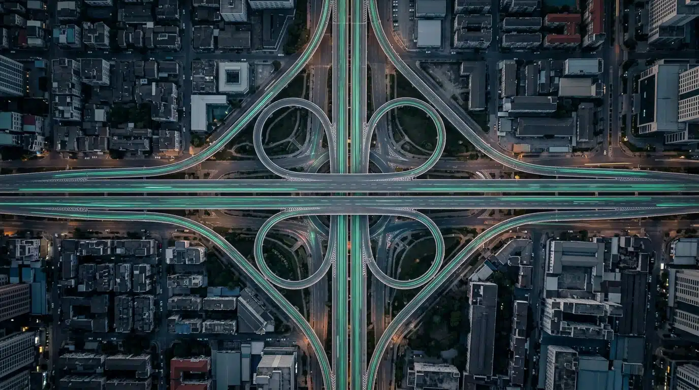 Aerial view of a city's highway network at dawn, showing dynamic green light trails from vehicles symbolizing future-forward business insights and proactive data analysis for growth strategies.